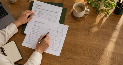 Illustrative overhead view of hands comparing invoice records and correspondence